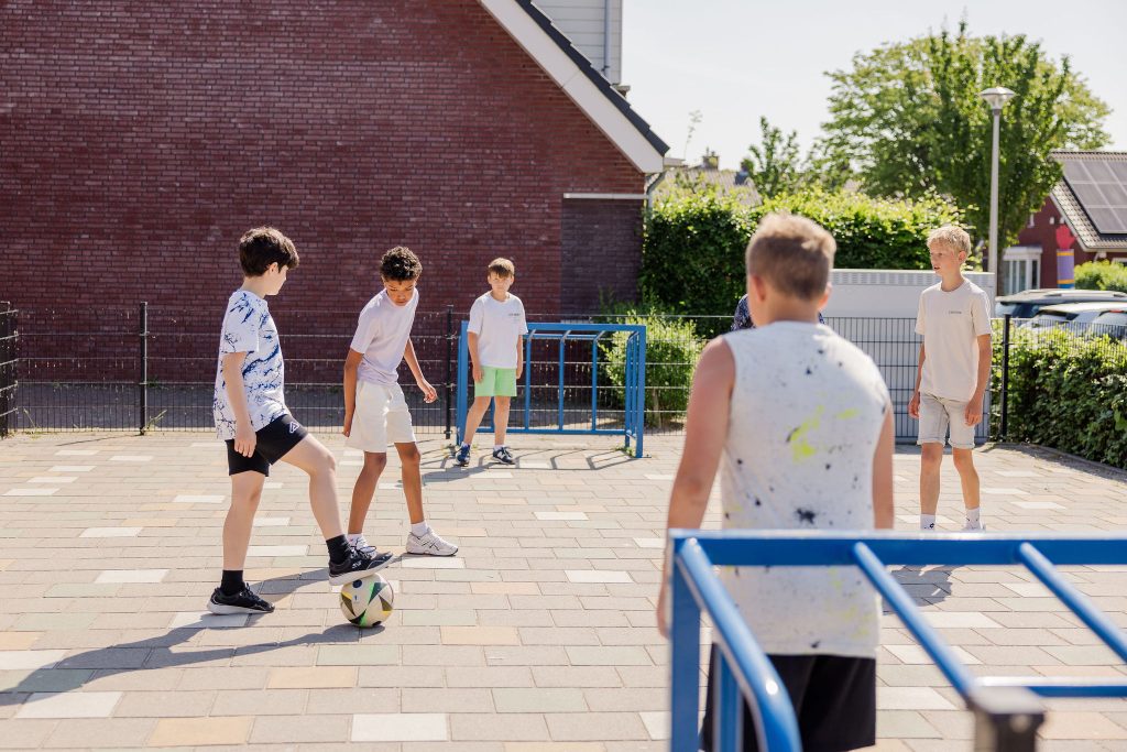 Jongens voetballen op schoolplein